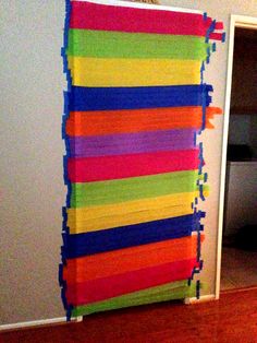 the room is decorated with colorful strips of duct tape on the wall, and there is a door in the background