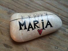 a rock with the word marina painted on it sitting on a wooden table next to a pen