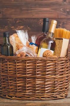 a wicker basket filled with wine, bread and other items on top of a wooden table