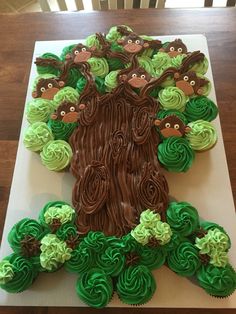 cupcakes are arranged in the shape of a tree with monkeys on it and green frosting