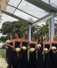 a group of women standing next to each other in front of a white flower arch