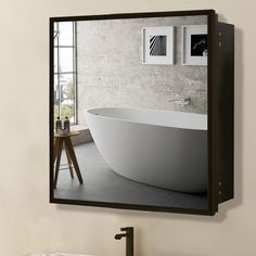 a white bath tub sitting next to a window in a bathroom under a mirror on the wall