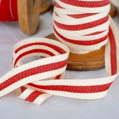 red and white striped ribbon sitting on top of a wooden spool