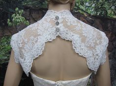 the back of a woman's wedding dress with white lace and beading on it