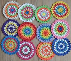 crocheted coasters are arranged on a wooden surface in different colors and sizes