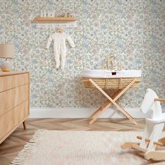 a baby's room with floral wallpaper and wooden furniture