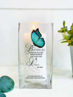 a candle with a butterfly on it next to a potted plant