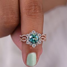 a woman's hand holding a ring with a blue and white diamond in it