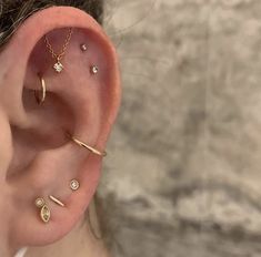 a woman wearing three different types of ear piercings