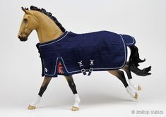 a toy horse wearing a blanket on it's head and tail, walking across a white surface