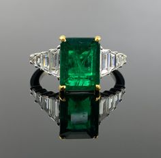 The vivid green of the emerald exudes timeless allure, while the surrounding diamonds add a touch of dazzling brilliance. Whether it's a special occasion or an everyday statement, this exquisite piece is a reflection of your refined taste and a cherished addition to your jewelry collection. Details: 18K Gold: 4.63 grams  Diamond - 0.78 Ctw Emerald - 3.13 Cts Luxury Green Diamond Ring With Vvs Clarity, Dazzling Green Diamond Ring With Brilliant Cut, Luxury Green Asscher Cut Diamond Ring, Luxury Green Emerald Diamond Ring, Luxury Green Diamond Ring With Brilliant Cut, Luxury Tsavorite Emerald Ring For Formal Occasions, Luxury Green Diamond Ring For Formal Occasions, Dazzling Green Diamond Ring, Luxury Green Diamond Ring For Anniversary