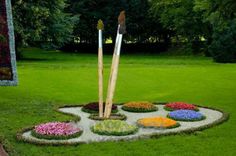 a circular garden with flowers and two wooden sticks in the center, surrounded by grass