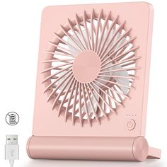 a pink portable fan sitting on top of a table next to an iphone charger