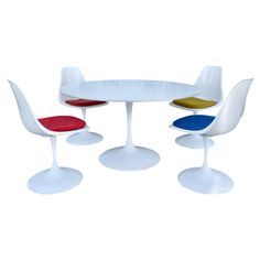 three chairs and a table with four different colors on the top one is red, yellow, blue, and white