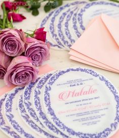 wedding stationery with purple roses and pink envelopes on a white tableclothed table