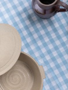 two dishes on a blue and white checkered tablecloth next to a coffee mug