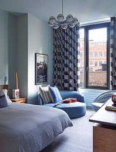 a bed room with a neatly made bed next to a chair and a large window