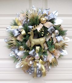 a christmas wreath with gold, silver and white decorations on the front door is shown