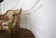 a chair sitting on top of a hard wood floor next to a white banister