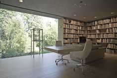 an office with a bookcase and desk in front of it, along with a large window