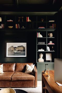 a brown leather couch sitting in front of a book shelf filled with lots of books