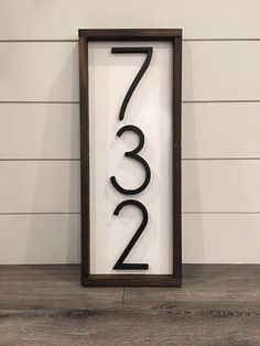 a wooden sign with the number twenty three in black on top of a wood floor