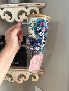 a person holding a coffee cup in front of a shelf with other items on it