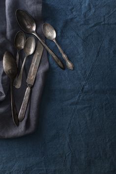 five spoons and two forks on a blue cloth