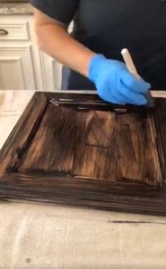 a person in blue gloves is cleaning a wooden tray