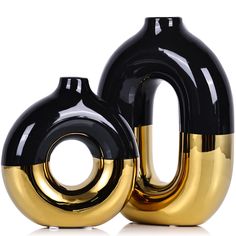 two black and gold vases sitting next to each other