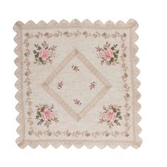 a white table cloth with pink roses on it and lace trimming around the edges