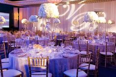 the tables are set with white flowers and blue linens for an elegant wedding reception