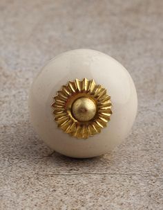 a white ball with a golden sun decoration on it's end sitting on the ground