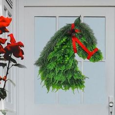 a wreath hanging on the front door of a house with red roses and greenery