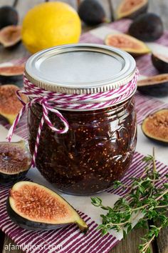 an open jar of fig jam next to sliced figs on a striped tablecloth