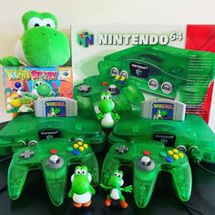 several green video game controllers sitting on top of a table next to a stuffed animal