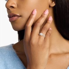 a close up of a woman wearing a ring and holding her hand to her face