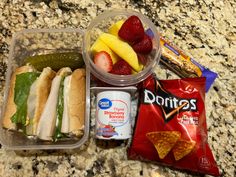 lunch box with sandwich, fruit, chips and yogurt on marble counter top