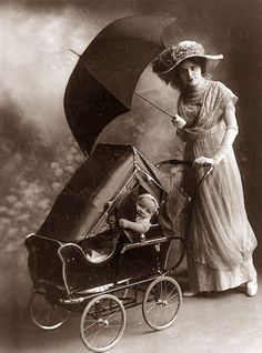 an old black and white photo of a woman pushing a baby in a stroller