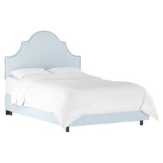 a bed with white sheets and blue pinstripe upholstered headboard