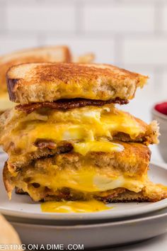 two grilled cheese sandwiches stacked on top of each other in front of a bowl of ketchup