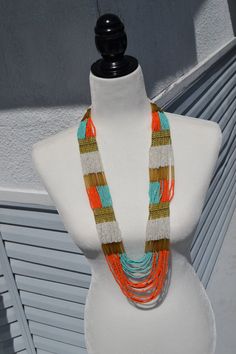 A gorgeous multi-color beaded necklace with dozens of individual strands of beads featuring colors of orange, blue, white and gold bead accents. Measures approximately 32" in total length. Buy 3 Ship Free (Put 3 items in your basket to realize free shipping) Orange Multi-strand Colorful Beads Jewelry, Orange Multi-strand Beaded Necklaces For Beach, Orange Multi-strand Beaded Necklaces, Orange Multi-strand Beaded Necklace, Orange Multi-strand Jewelry For Beach, Orange Multi-strand Jewelry For The Beach, Handmade Multi-strand Orange Beaded Necklaces, Multi-strand Beaded Long Costume Necklace, Beaded Multi-strand Costume Jewelry Necklace