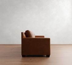 a brown chair sitting on top of a hard wood floor next to a white wall