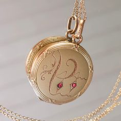 "Sweet romantic locket from the Art Nouveau/Jugendstil era. Fine hand engraved pattern at the front with two ruby paste stones. Ornate relief frame going all around, with little bows. The back is plain. Details: The locket is from the Art Nouveau era, early 20th century. It is stamped \"FIX\" at the bale, which stands for a high quality 18k gold plating popular in France at Victorian times. Condition: It is in very good antique condition. Some light surface wear, scratches and a nice patina to the outside. There is no dent that I can see. Inside there is some oxidation, please inspect the photos. The two original rings are present, reasy to hold your photos. It closes tightly with a snap. The locket is sold with a new 18\" gold filled chain that is stamped 1/20 14k at the clasp. Measuremen Original Rings, Victorian Times, Locket Necklace, Gold Filled Chain, Hand Engraving, Early 20th Century, Gold Plating, French Antiques, Locket