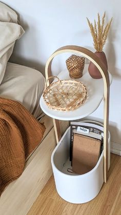 a small table with magazines on it next to a bed and a plant in a vase