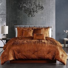 a bedroom with a large bed covered in brown comforter and pillows next to a chandelier