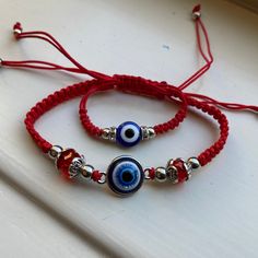 two red string bracelets with evil eye beads