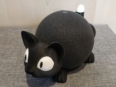 a black and white cat figurine sitting on top of a gray carpeted floor