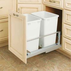 two white trash cans are in the pull out cabinet for extra storage and space to store them