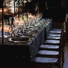 a long table is set up with glasses and candles for an elegant dinner or party